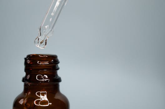 Close-up of a glass dropper with liquid from an amber bottle, representing acid testing avoided in modern gold evaluation
